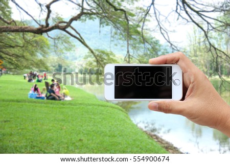 man use mobile phone. blur image of people exercise in the park as background.