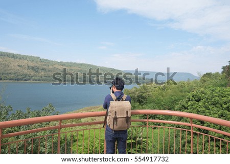 Backpack Photographer with his camera, jean jacket and bag with scenic view point in thailand