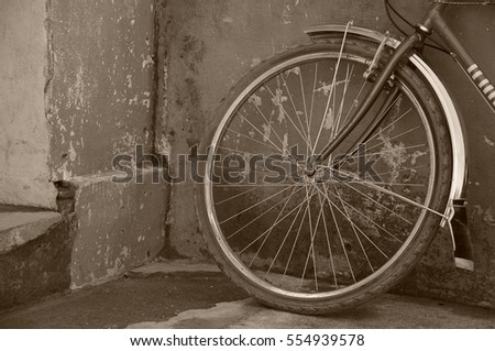 old bicycle tire leaning on old rusted wall in vintage, sepia mood
