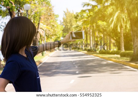 Woman enjoying in nature and taking picture in the garden with mobile phone.