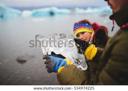 man and woman looking at piece of ice at lake