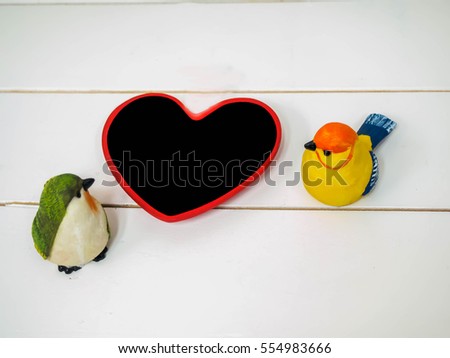 bird dolls made of stucco on white chair background with small board heart , black space for insert text or image