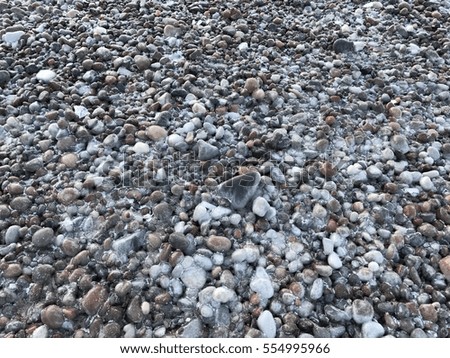 The pebbles on the beach in winter under the ice