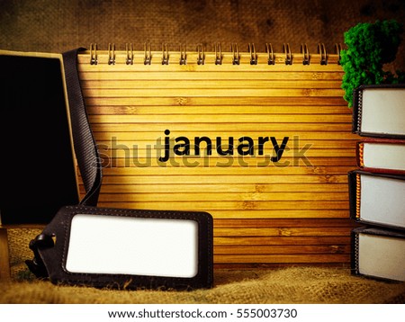 Business and Education Concept. hard case cover, staff tag, multiple books over the canvas written January