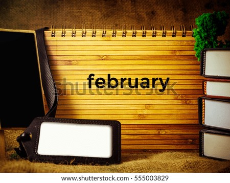 Business and Education Concept. hard case cover, staff tag, multiple books over the canvas written February