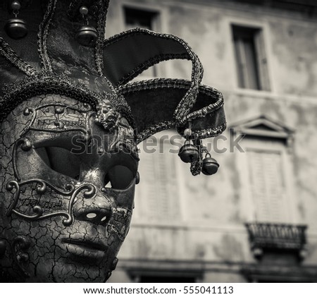 Venetian  carnival mask and old palazzo at background. Venice (italy). Dark black and white photo.