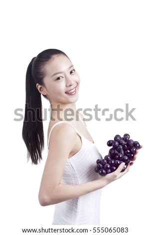 	young woman holds a bunch of grapes in her hand	