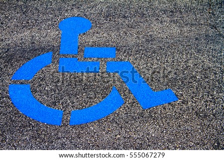Handicap Parking Emblem painted in Blue paint in a parking lot.