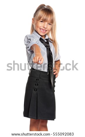 Smiling little school girl pointing finger to you, isolated on white background. Happy child pointing at camera choosing you. 