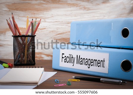 Facility Management, Office Binder on Wooden Desk. On the table colored pencils, pen, notebook paper