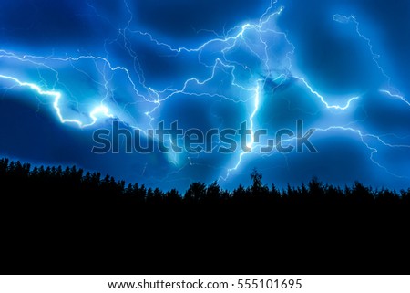 Lightning strike on a dark blue sky over the forest silhouette