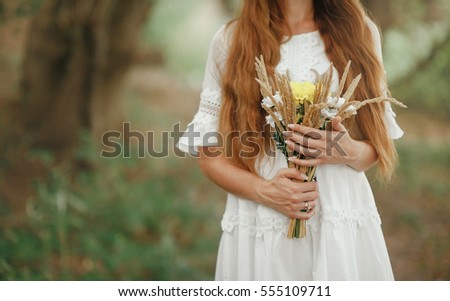 girl in a white sundress with  bouquet of wildflowers