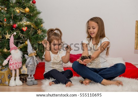 Two girls sitting under Christmas tree