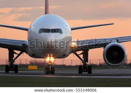 Modern civil passenger airliner taking off at airport during sunset. Royalty-Free Stock Photo #555148006
