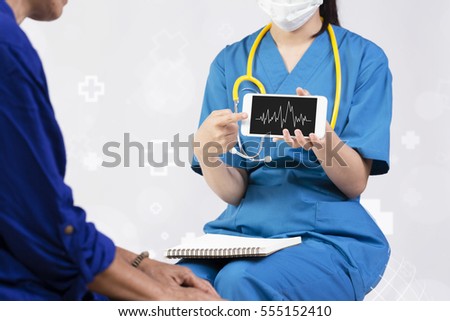 Female doctor showing heart rate monitor application on mobile to her elderly patient over abstract white background with hospital icon.