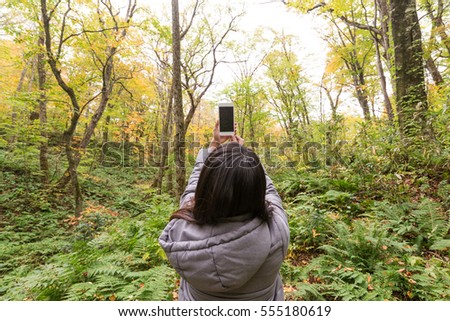 Back view of woman taking photo at forest