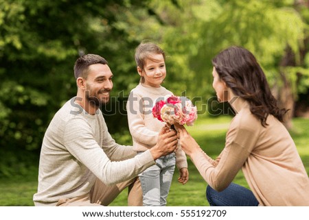 family, holidays and people concept - happy father and little girl giving flowers to mother in summer park