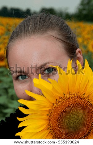 Beautiful happy young blond woman with bright lights sunflowers on an agricultural field. Portrait of a white beautiful young woman with a sunflower