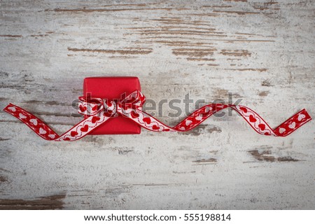 Wrapped gift with red ribbon on old wooden background, decoration for Valentines Day