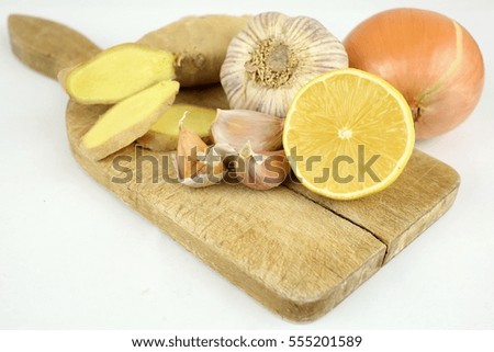 Natural treatment. Closeup of a wooden board placed garlic, ginger, lemon, onion. Natural medicine for flu, bronchitis and colds. Wooden board resting on a white background. Isolated.