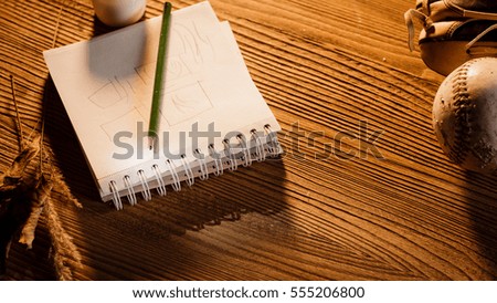 The notepad, pen and coffee on the grunge wooden table with warm light inside the cottage. Wood blurred background. View from above.