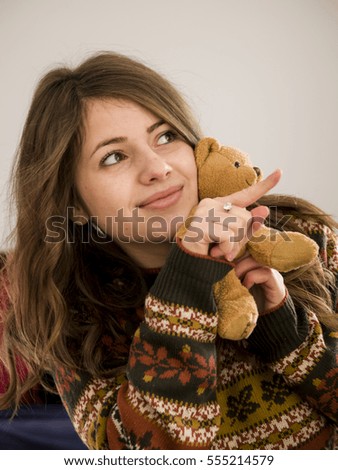 Young girl watching something with her teddy bear
