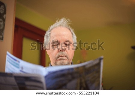 Senior man reading a newspaper in livingroom