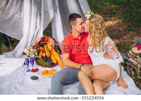 Young enamoured couple on picnic in wood. Funny moment. Eating grape. Lovely together.