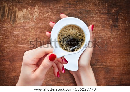 woman holding hot cup of coffee on wooden table