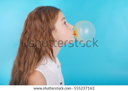 Young girl doing bubble with chewing gum blue background
