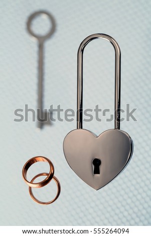 wedding rings, steel lock and key on light background