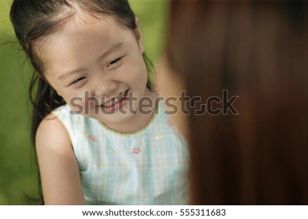 Young girl smiling, mother looking on