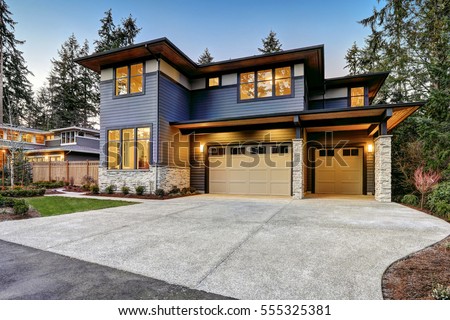 Luxurious new construction home in Bellevue, WA. Modern style home boasts two car garage framed by blue siding and natural stone wall trim. Northwest, USA Royalty-Free Stock Photo #555325381