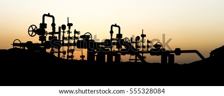 Silhouette of crude oil manifold in the oilfield at sunset  Royalty-Free Stock Photo #555328084