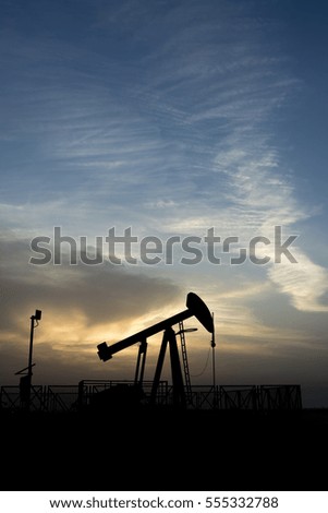 Silhouette of crude oil pump in the oil field at sunset blue hour 