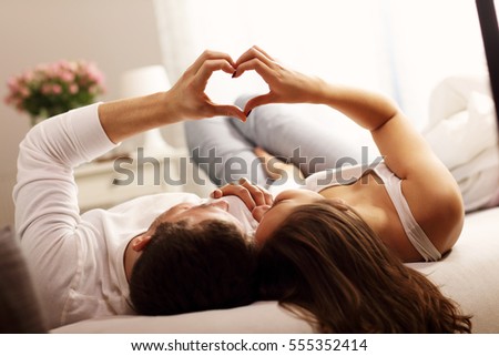 Picture showing happy couple making heart shape in bedroom
