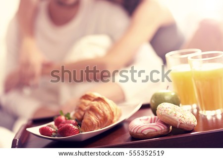 Picture of young couple eating breakfast in bed