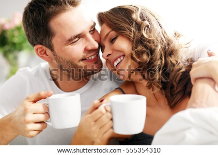 Picture of young couple drinking coffee in bed