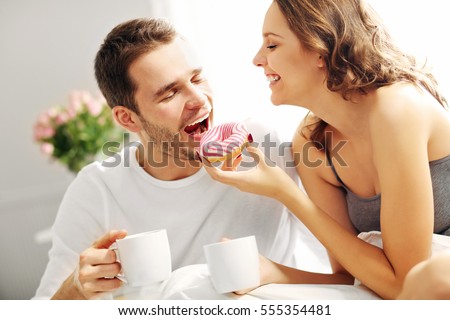 Picture of young couple eating breakfast in bed
