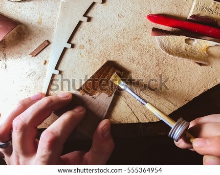 Boat modeling hobby wallpaper. men with a brush in his hand put the varnish on the little piece of wooden element of the boat model background. Hobby education surface