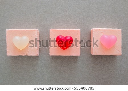 three pink cake with marmalade in the form of heart on grey background