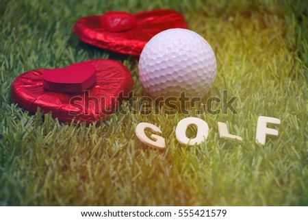 golf ball with red heart shape chocolate are on green grass, Idea for golfer love concept.