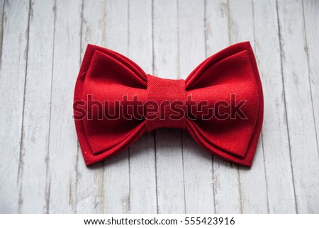 Men's red bow tie on a wooden background. Accessory for formal dress. Symbol of elegance and fashion for men. Bow tie man. Men's and women's accessories. Royalty-Free Stock Photo #555423916