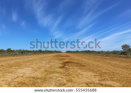 Long red dusty road in the Australian outback Royalty-Free Stock Photo #555435688