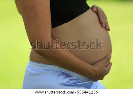 Pregnant Woman on green grass and red flower on the hair