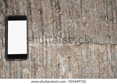 Black phone with blank white screen on cracked concrete floor desktop. Topview, Mock up