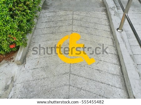Wheelchair sign on concrete floor indicates route for people on wheelchair.