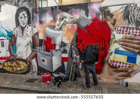 Street art artist paints graffiti inspired by the Red Cross on the streets of the historic center of Valencia, Spain