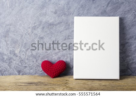 Love concepts of red heart and blank canvas frame on wood table for valentines day and wedding