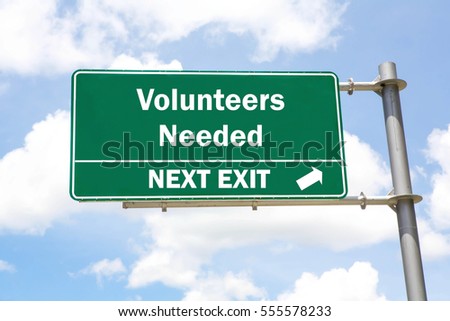 Green overhead road sign with a Volunteers Needed Next Exit concept against a partly cloudy sky background.